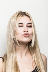 Close-up portrait of a young beautiful blonde girl on a light background. A woman with different emotions on her face.