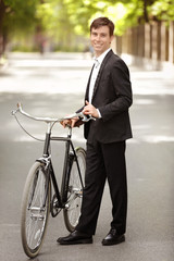 Young handsome businessman with bicycle outdoors on sunny day