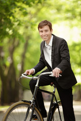 Young handsome businessman with bicycle outdoors on sunny day