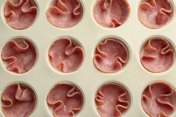 Muffin tin with tasty slices of ham, closeup