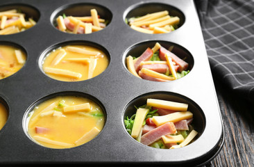 Whipped eggs, sliced cheese and ham in baking mold on table, closeup