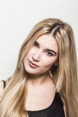 Naklejka premium Close-up portrait of a young beautiful blonde girl on a light background. A woman with different emotions on her face.