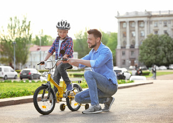 Dad teaching son to ride bicycle outdoors