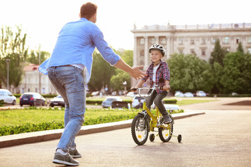 Dad teaching son to ride bicycle outdoors