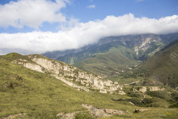 Fototapeta na wymiar Горный пейзаж. Красивый вид на живописное ущелье, панорама горной местности, белые облака на синем небе. Природа и горы Северного Кавказа