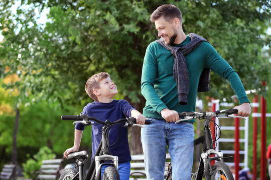Dad and son walking with their bicycles outdoors
