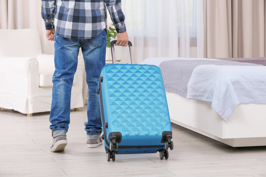 Young man with luggage in hotel room