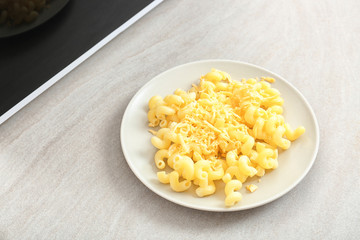 Plate with pasta and cheese near microwave on table
