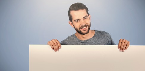 Composite image of portrait of smiling man holding cardboard