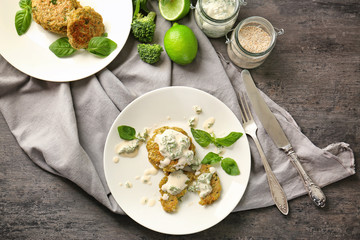 Broccoli pancakes served with sauce, parsley and basil leaves on white plate