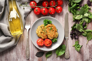 Composition with broccoli pancakes, cherry tomatoes, oil and basil leaves on wooden table