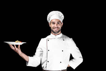 Young male chef presenting his dish on black background
