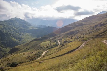 Горный пейзаж. Красивый вид на живописное ущелье, панорама горной местности, белые облака на синем небе. Природа и горы Северного Кавказа