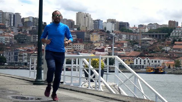 Young man jogging in city near river, super slow motion 240fps
