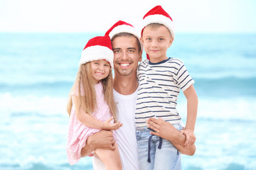 Young father with cute children on beach. Christmas concept