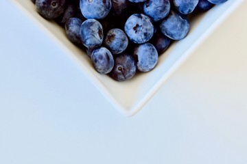 Tasty blueberry in the white square plate on the white table (half of plate)
