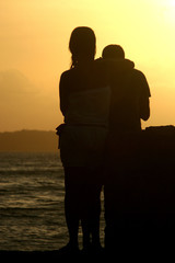 Romantic couple on the beach in Brazil at colorful sunset on background