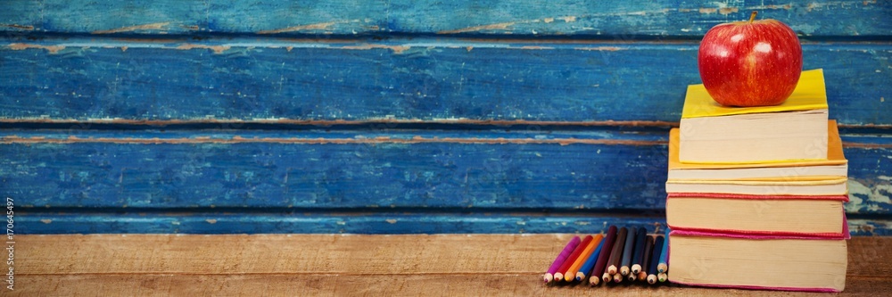 Poster apple with stacked books and pencils on table