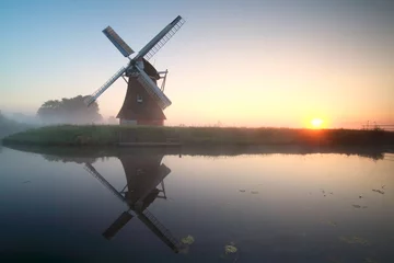 Photo sur Plexiglas Moulins charming windmill by lake at sunrise
