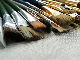 Big variety of brushes, tools for painting and sculpture on linen fabric background. Art background. Different shapes and sizes. 