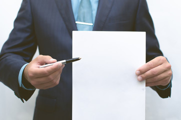 Contract conclusion. Signing of the contract. Business man holding blank document page in front of...