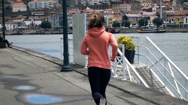 Young woman jogging in city near river, super slow motion 240fps
