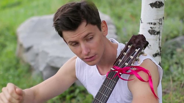Rest with a guitar under a tree. The young bard sat down to rest