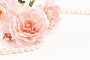 Close up of pearl necklace and pink roses