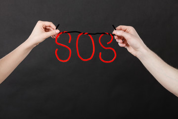 Two hands holding red SOS sign
