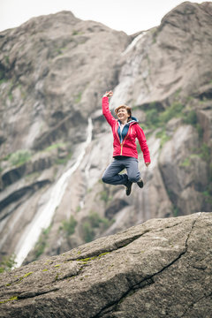 Happy woman jumping on rock in mountains