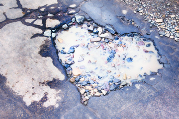 road pothole in the form of the heart of lovers is flooded with puddles along with gravel and cracks stones