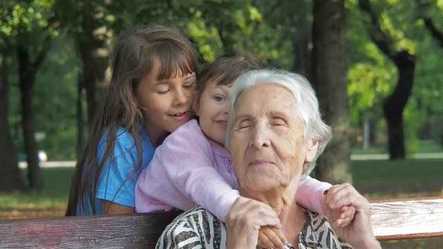 Happy granddaughters hug grandmother. Little girls hug grandmother.