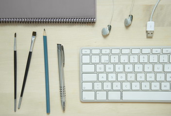 computer keyboard pen pencil notepad white earphone on wood table business office lay flat