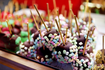 Apples dip in chocolate icing and small marshmallows sold on Christmas market. Candies, sweets and desserts on Xmas time.