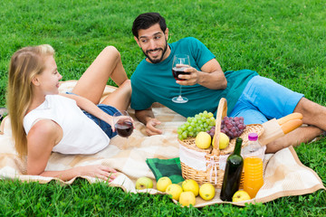 Smiling couple is lying with wineglasses and talking