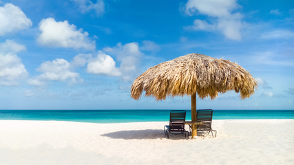 Straw umbrella on Eagle Beach, Aruba on a lovely summer day - obrazy, fototapety, plakaty