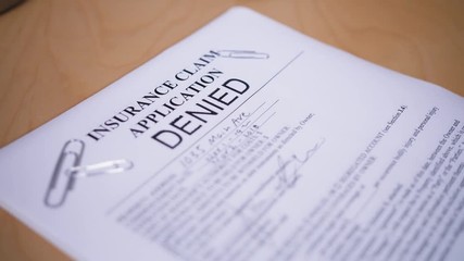A slow motion shot of a manager denying a customer's insurance claim application.  	