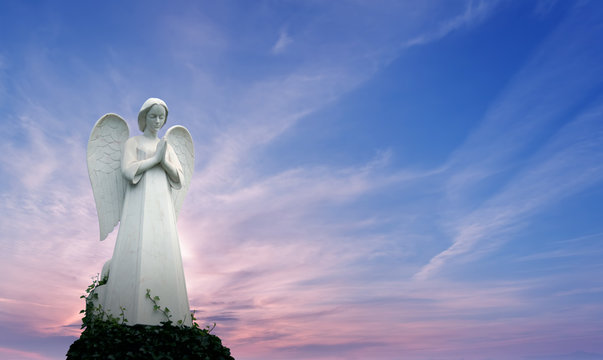 Angel sculpture over bright sky