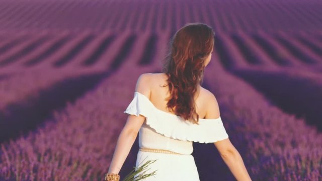 Happy Young Woman Enjoying Nature in Lavender Field. SLOW MOTION 120 FPS. Calm joyful girl in endless blooming lavender fields. Plateau du Valensole, Provence, France, Europe.