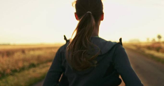 Woman Running on a Countryside Road at Sunrise. SLOW MOTION 4K DCi. Female jogger athlete training at dusk. Active healthy lifestyle concept. Cinematic sports shot. 