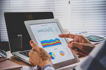 Close-up of a tablet computer with financial data on screen in hands of businessman and working.