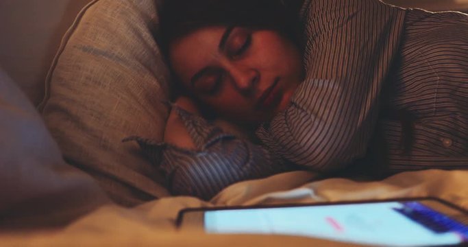 Woman Sleeping with Lights on at Night. SLOW MOTION 4K DCi. Young woman fell asleep while using digital tablet. Tired person.