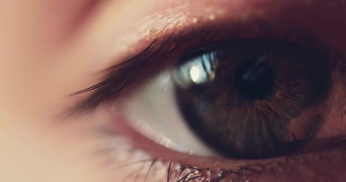 Macro Close-up Eye Blinking. SLOW MOTION 4K DCi. Young Woman is opening and closing her hazel eye. Eyesight health. Cinematic close up shot on dark background.