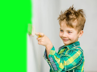 Happy boy painting the wall with paintbrush