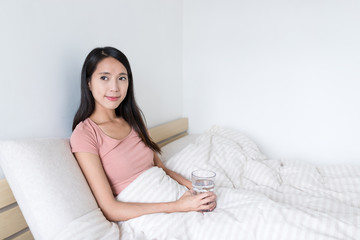 Woman holding glass of water and looking out of window