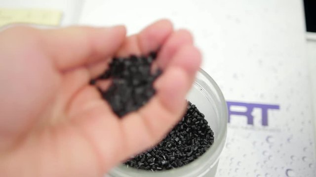 Plastic granules of polycarbonate in hand - extrusion manufactory