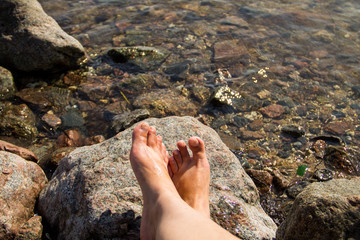 Woman's bare feet near the sea on rock