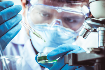 Conical flask in scientist hand with microscope and lab glassware background, Laboratory research concept