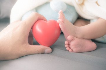 baby's feet with a red heart