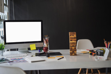 Stylish workspace with desktop and laptop computer, office supplies, houseplant and books at home or studio. Blank screen for graphics display montage.